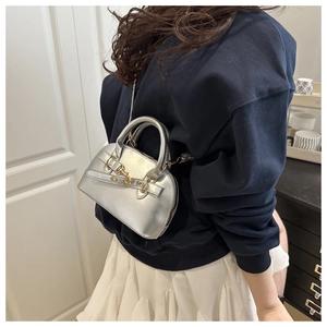 Dettaglio della mini borsa metallizzata argento con finiture dorate su un modello