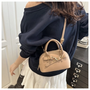 Detail view of khaki shell crossbody bag with golden hardware and adjustable strap