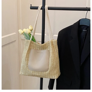 Détail d'un sac cabas en paille avec poche frontale en cuir et anses en corde tressée