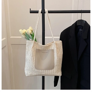 Détail du sac cabas en paille tressée avec poche frontale en cuir et anses en corde de coton