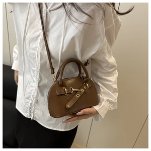 Detailed view of dark brown shell crossbody bag with golden buckle and sleek leather finish