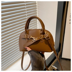 Dettaglio mini borsa a sella in pelle marrone con fibbia dorata e manico a cilindro