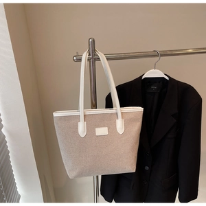 Detail view of durable canvas texture and white leather trims on the casual tote bag