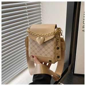 Détail du sac bandoulière monogramme beige avec fermoir cœur doré et chaîne en métal