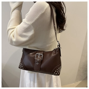 Détails des clous argentés et de la grande boucle en métal sur ce sac à bandoulière marron