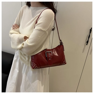 Gros plan du sac cabas en cuir rouge avec rivets argentés et boucles métalliques sur modèle