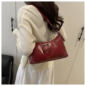 Detail showing vintage red tote bag with silver buckle and metal studs on a model