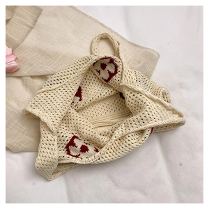 Détail du sac cabas beige crocheté avec motif de fleur rouge et texture tissée