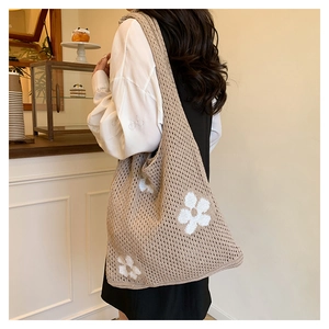 Détail du sac cabas en crochet beige avec motifs de fleurs blanches porté par un mannequin