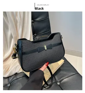 Dettaglio della borsa a spalla nera con fiocco chic e ganci in metallo dorato
