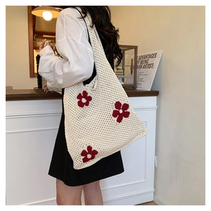 Close-up of cream crochet tote bag featuring red floral knit patterns and hollow mesh texture