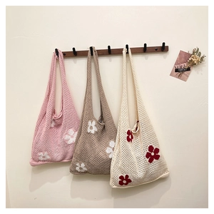Détail de sacs fourre-tout en tricot faits main avec motifs floraux en trois couleurs douces