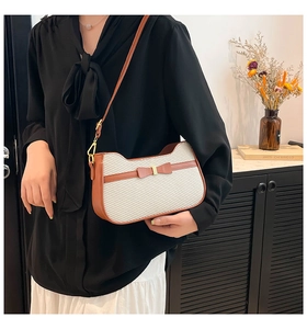 Detail of cream herringbone weave bag with brown leather trim and bow on model