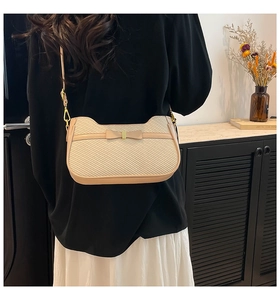 Detail of cream woven shoulder bag with ribbon bow and elegant gold metal buckle