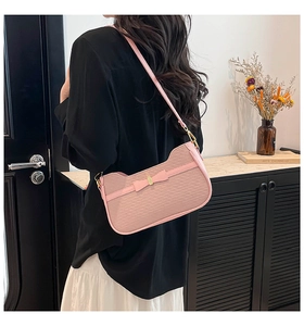 Pink fabric underarm bag with twill texture and decorative bow on model's shoulder