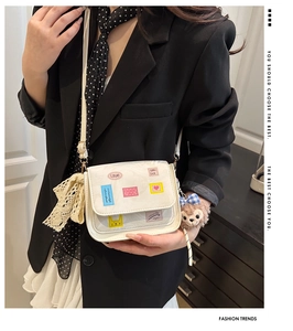 Detail of white tote bag featuring colorful embroidery and cute plush bear charm