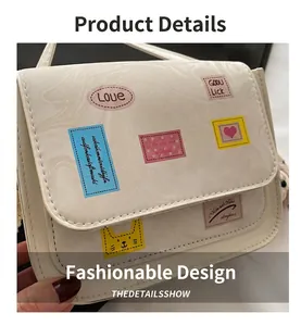 Detail of a creamy white PU leather shoulder bag with colorful cartoon prints and patches