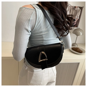 Detailed view of black saddle bag with gold buckle worn with casual casual outfit