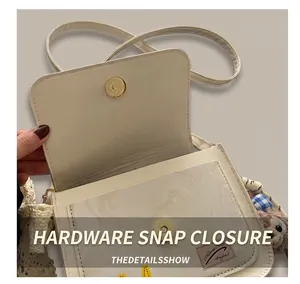 Close-up of minimalist cream PU leather crossbody bag with gold magnetic clasp and monkey charm