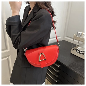 Detail of red saddle bag with gold horseshoe buckle worn on black blazer