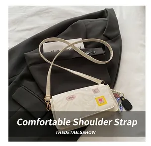 Detail of adjustable PU leather strap and colorful letter patches on white crossbody bag