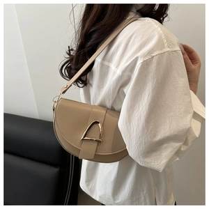 Detail showing the apricot saddle bag with gold metal buckle on a model shoulder