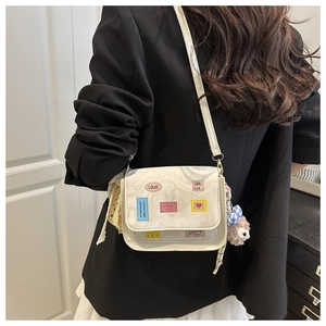 Detail of white marble textured crossbody bag with cute charms and lace ribbon accents