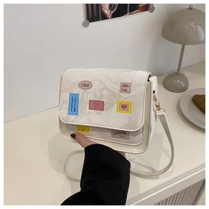 Detail of white marble textured bag with colorful cartoon labels and gold strap hooks