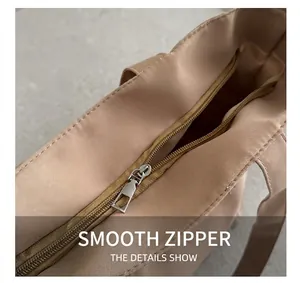 Detail view of smooth metal zipper closure on beige canvas tote bag with fabric texture