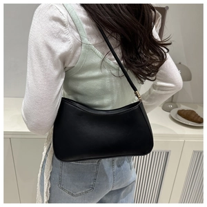 Rear view of model wearing a black minimalist moon bag with gold hardware details