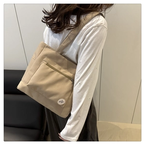 Detail of khaki canvas tote bag with front zipper pocket and good luck embroidery