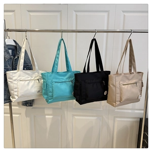 Detailed display of tote bags in four colors with front zipper and side pockets
