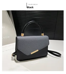 Close-up of black leather handbag with grey denim flap and gold clasp hardware
