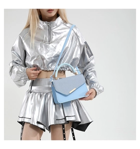 Detail of light blue crossbody bag with glitter flap and golden metallic hardware