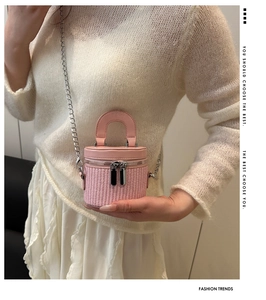 Close-up of pink woven cylindrical bucket bag with dual zippers and silver chain strap