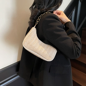 Minimalist beige woven crescent underarm bag with elegant gold chain strap on model