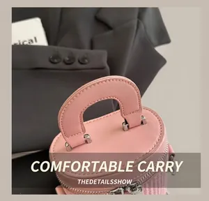 Detail of pink cylindrical bucket bag with woven texture base and dual zipper closure