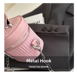 Close-up of pink woven bucket bag featuring silver metal chain and hardware hook detail