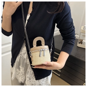 Detail of mini woven bucket bag featuring premium beige leather trim and silver metal chains