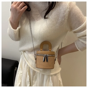 Close-up of mini cylindrical woven bucket bag with leather trim and silver chain