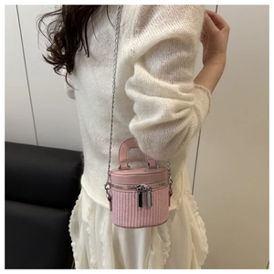 Detail of pink woven bucket bag with dual zippers and elegant metallic chain strap