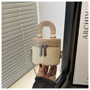 Close-up of woven bucket bag featuring dual metal zippers and elegant leather handle