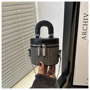 Detail of cylindrical bucket bag featuring woven pattern and double silver zippers