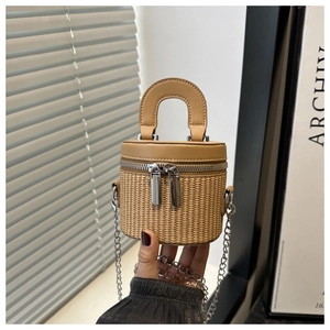 Close-up of khaki woven bucket bag featuring dual zippers and elegant metal chain strap