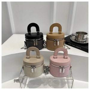 Close-up of four woven cylinder bucket bags in black, brown, beige, and pink colors