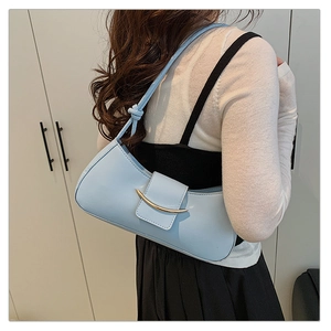 Rear view of a light blue underarm bag with knot detail on strap worn over a black dress