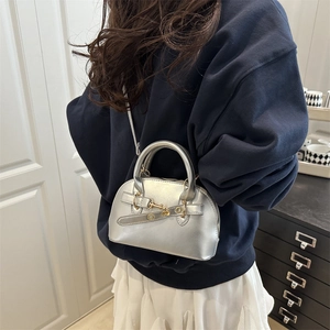 Metallic silver shell-shaped handbag with decorative belt and gold hardware