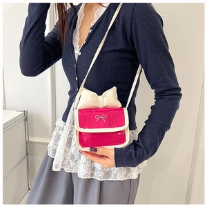 Detail of rose pink mini crossbody bag with cream bow and crocodile texture on model