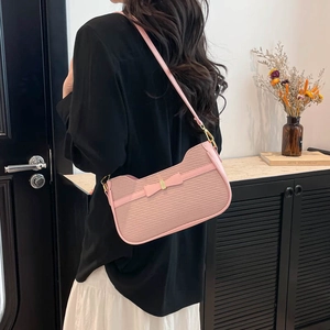 Pink embossed faux leather underarm bag with bow detail on a fashion model