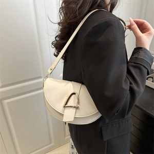 Minimalist cream white faux leather saddle bag with gold metal buckle and wide shoulder strap
